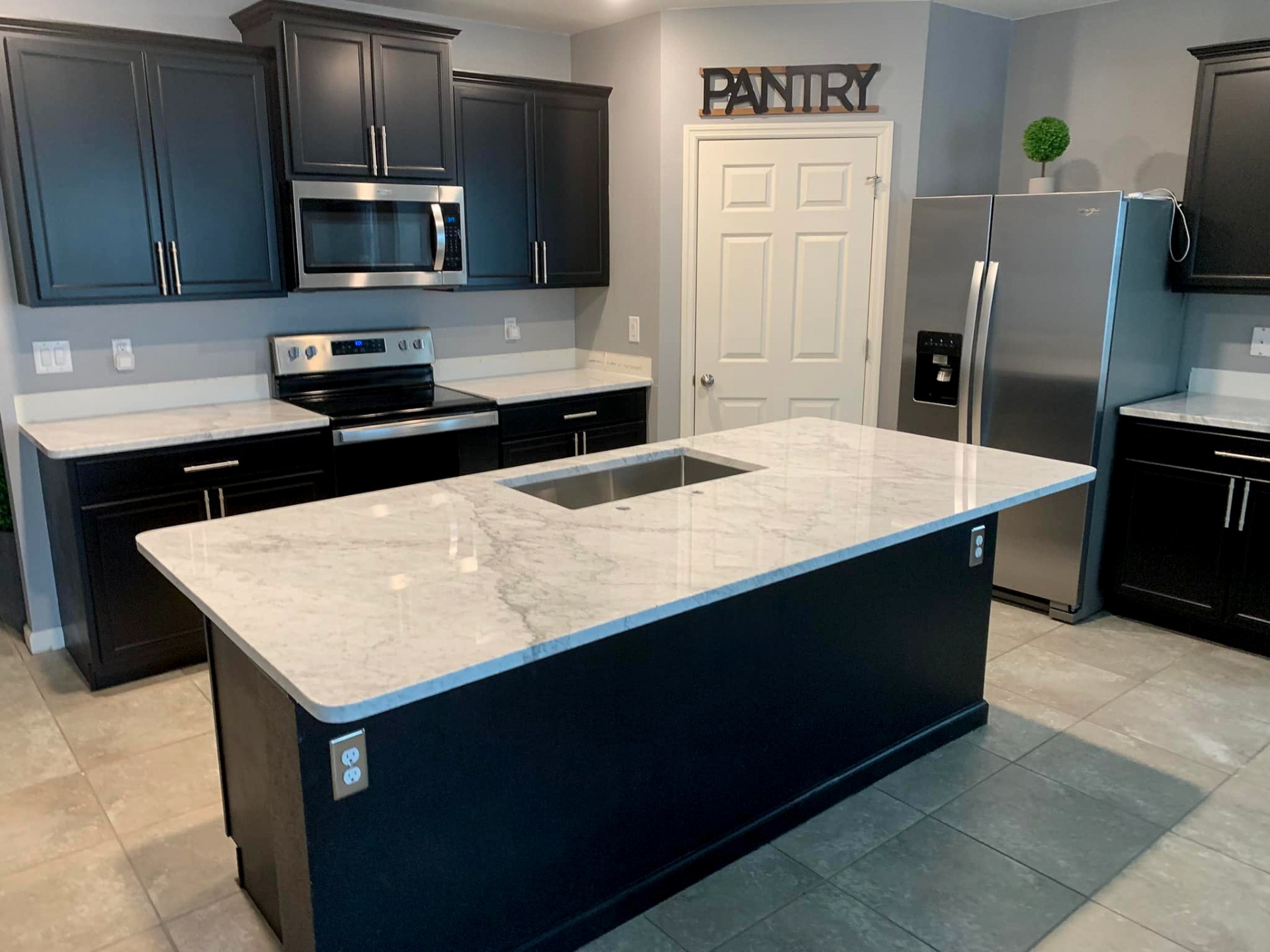 Completed kitchen remodel with dark cabinets and white marble island by Horizon Elite Renovations